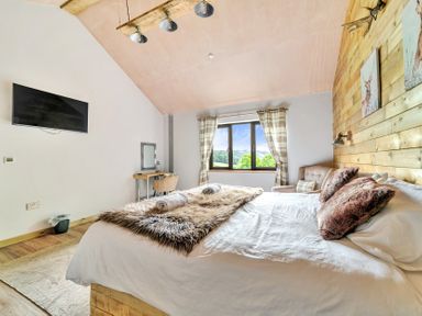 A bedroom with a bed and window view at Bwncath in Garthmyl