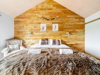 A bedroom with a bed and armchair at Bwncath in Garthmyl