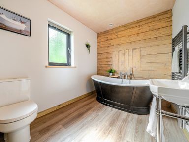 A bathroom with a bathtub, toilet, and sink at Bwncath in Garthmyl