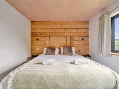 A bedroom with a bed and wooden wall at Bwncath Garthmyl