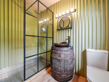 A bathroom with a shower, sink in a barrel and toilet at Bwncath in Garthmyl