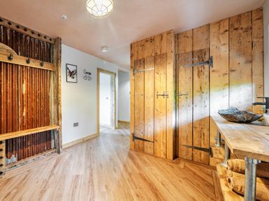 A hallway with wooden cabinets and wall hooks at Bwncath in Garthmyl