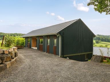 A building with a pathway and bushes at Bwncath in Garthmyl