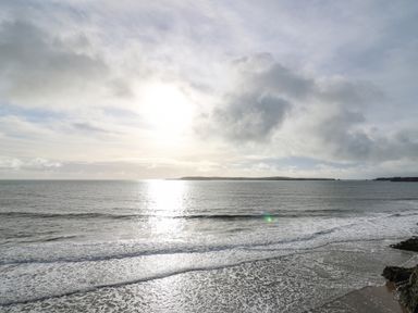 A view of the ocean with waves near a rocky shore under a cloudy sky at 1 St Marys Court in Tenby