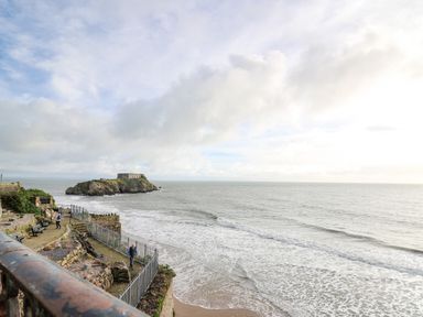 A coastal view with a rocky island and a building in the sea at 1 St Marys Court in Tenby