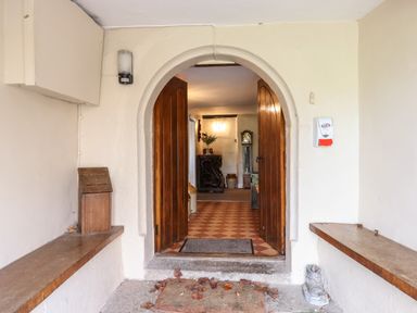 An entryway with open wooden doors leading to a tiled floor and furniture inside at Twelve Oaks Farmhouse in Teigngrace near Newton Abbot