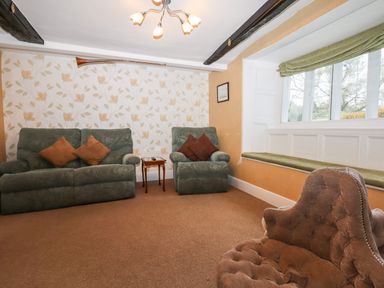 A sitting room with upholstered armchairs a small wooden side table and a window seat at Twelve Oaks Farmhouse Teigngrace near Newton Abbot