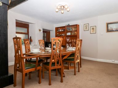 A dining room with wooden table and chairs set with plates and glasses at Twelve Oaks Farmhouse in Teigngrace near Newton Abbot
