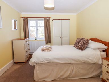 A bedroom with a bed bedside table dresser wardrobe and window with curtains at Twelve Oaks Farmhouse in Teigngrace near Newton Abbot