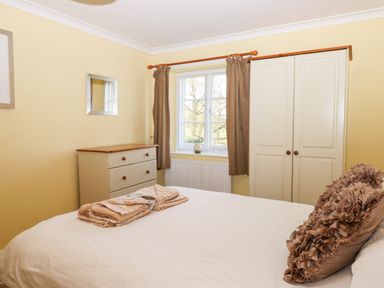 A bedroom with a bed curtains wardrobe and chest of drawers at Twelve Oaks Farmhouse in Teigngrace near Newton Abbot