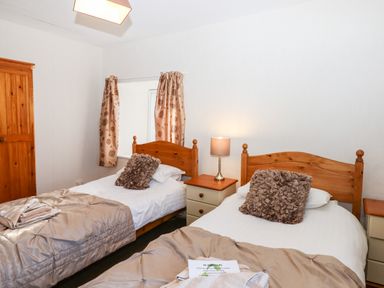 A bedroom with two single beds bedside tables a lamp and a wooden wardrobe at Twelve Oaks Farmhouse in Teigngrace near Newton Abbot