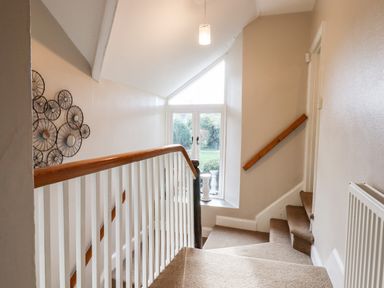 A stairway with a wooden handrail and a window at the landing at Twelve Oaks Farmhouse in Teigngrace near Newton Abbot