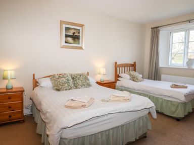 A bedroom with a double bed and a single bed with bedside tables and lamps at Twelve Oaks Farmhouse in Teigngrace near Newton Abbot