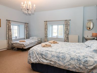 A bedroom with two beds a chandelier curtains and a sink at Twelve Oaks Farmhouse in Teigngrace near Newton Abbot