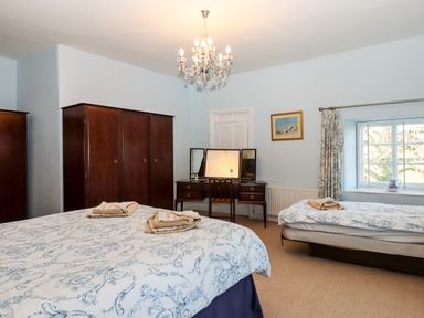 A bedroom with two beds a wooden wardrobe a dressing table and a window at Twelve Oaks Farmhouse Teigngrace near Newton Abbot