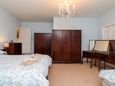 A bedroom with two wooden wardrobes a dressing table with mirrors and a bed at Twelve Oaks Farmhouse in Teigngrace near Newton Abbot