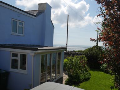 A blue house with a garden and stone wall near the sea at Fisherman's Cottage in Southwell