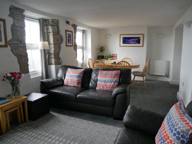 A living room with black leather sofas and a wooden dining table with chairs at Fisherman s Cottage in Southwell