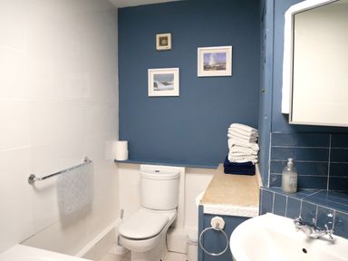 A bathroom with a toilet towels sink and mirror at Fisherman's Cottage in Southwell