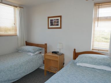 A bedroom with two single beds a wooden nightstand a lamp and a framed picture on wall at Fisherman's Cottage in Southwell