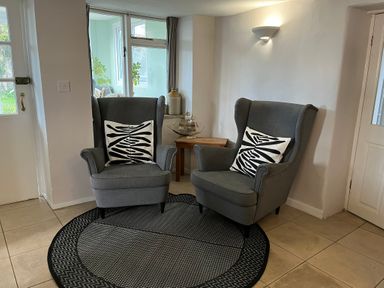 Two grey armchairs with black and white patterned cushions on a round black and grey rug in a tiled room at Fisherman's Cottage in Southwell