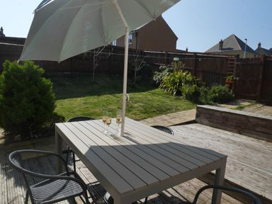 A garden patio with a table umbrella chairs and glasses on the table at Cliffwalk Cottage in Southwell