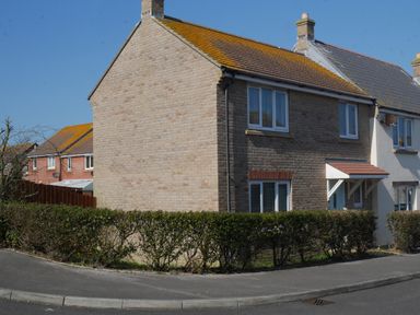 A semi detached house with brick and stone exterior and hedge on the corner of a street at Cliffwalk Cottage in Southwell