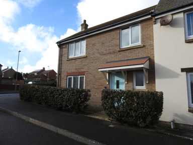 A brick residential house with blue front door and hedge along the sidewalk at Cliffwalk Cottage in Southwell