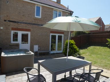 A backyard with a hot tub patio table chairs and umbrella at Cliffwalk Cottage in Southwell