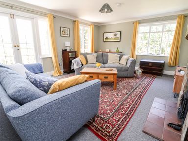 A living room with two blue sofas a wooden coffee table a patterned rug and yellow curtains at Melbecks in Abergele