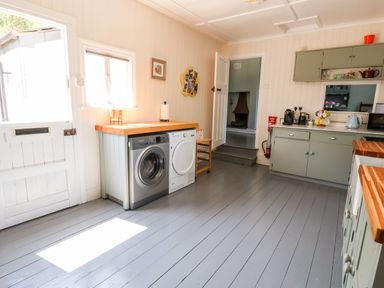 A kitchen with washing machine, dryer, cupboards, and countertop appliances at Melbecks Abergele