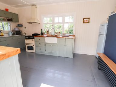 A kitchen with gray cabinets a white sink a stove a microwave a refrigerator and wooden countertops at Melbecks in Abergele
