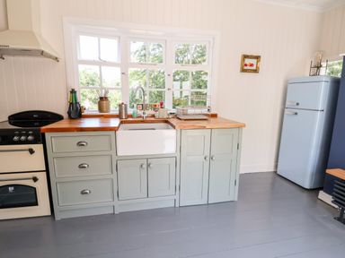 A kitchen with wooden countertops a white sink a light blue refrigerator and a stove at Melbecks in Abergele