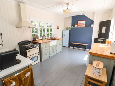 A kitchen with a black stove and oven next to wooden counters and a blue refrigerator with a blue wall at Melbecks in Abergele