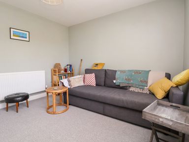 A living room with a gray sofa cushions and a wooden side table at Melbecks in Abergele