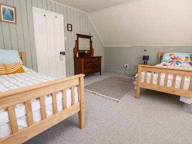 A bedroom with two wooden single beds a wooden dresser with mirror and a rug on the floor at Melbecks in Abergele