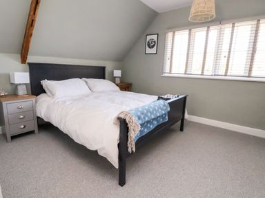 A bedroom with a double bed white bedding bedside tables with lamps and a window with blinds at Melbecks in Abergele