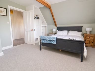 A bedroom with a double bed featuring white bedding and a blue star blanket with bedside tables and lamps at Melbecks in Abergele