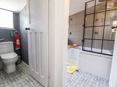 A bathroom with a toilet and a bathtub separated by a door at Melbecks in Abergele