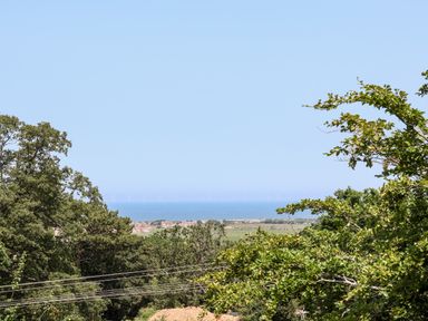 A landscape view with trees in the foreground a town and sea in the background with wind turbines at Melbecks in Abergele