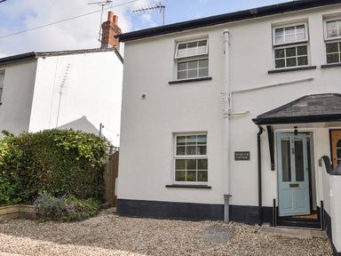 The exterior of a white two-story cottage with black trim and a blue front door at River Lym Cottage in Lyme Regis