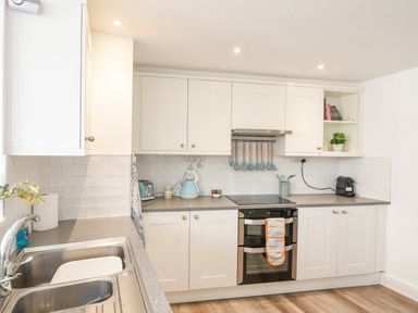 A kitchen with white cabinets a double oven and sink at River Lym Cottage Lyme Regis