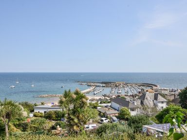 A coastal view with houses trees and a harbor filled with boats at River Lym Cottage in Lyme Regis