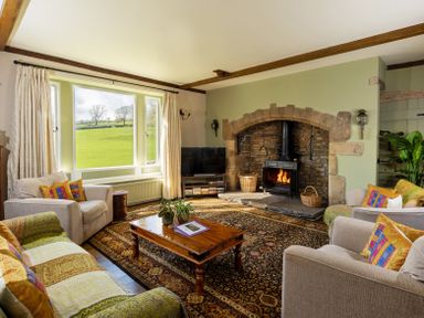 A living room with a wood-burning stove fireplace a wooden coffee table and armchairs at The Lodge in Hartlington near Grassington