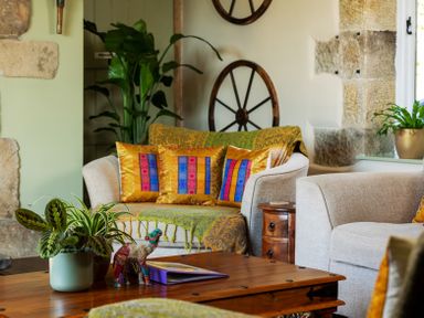 A living room with a wooden coffee table plants and colorful cushions on sofas at The Lodge in Hartlington near Grassington