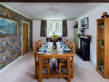 A dining room with a wooden table set for six people with plates glasses and napkins at The Lodge in Hartlington near Grassington