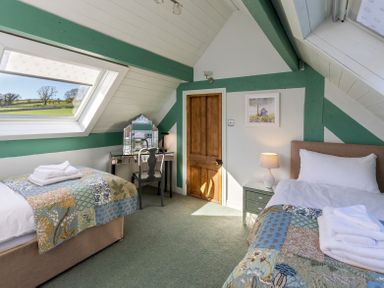 A bedroom with two beds a desk and chair and a wooden door at The Lodge in Hartlington near Grassington