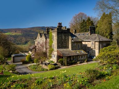 An old stone house with a garden and trees on a hillside at Kail House in Grassington