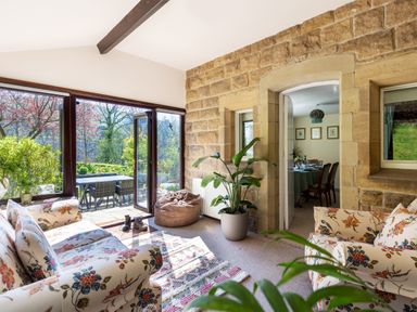 A sitting area with floral sofas and a bean bag near large glass doors opening to a patio at Kail House in Grassington