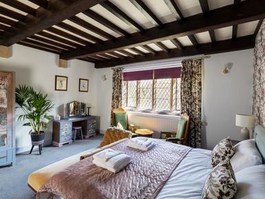 A bedroom with a bed towels on it two green chairs a dressing table and a potted plant at Kail House in Grassington